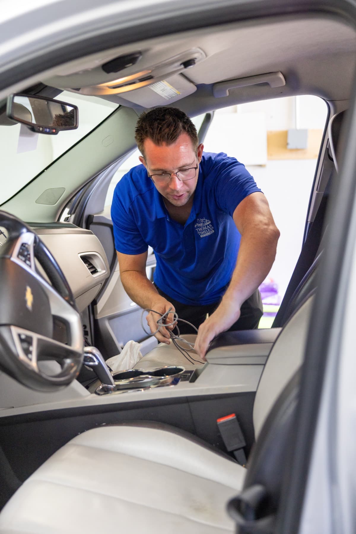Thomas working the center console of a client vehicle with quiet focus